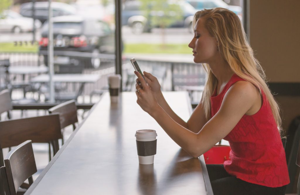 woman sitting alone in table with phone in her hands